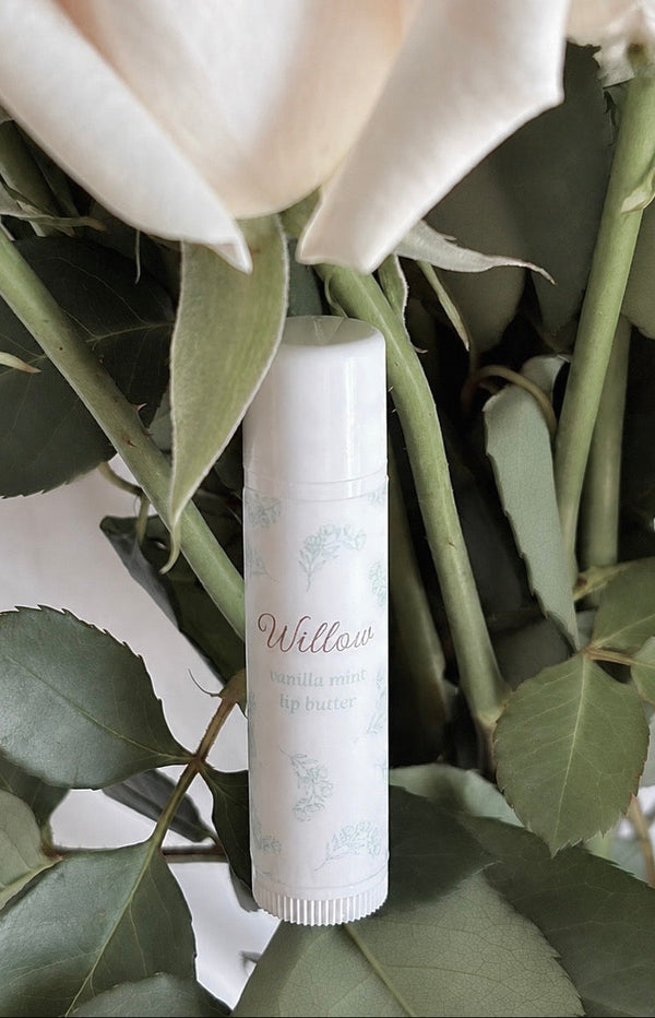 White cylindrical product with 'Willow' branding among green leaves and white flowers
