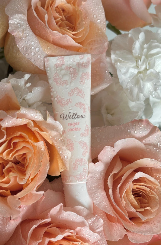 Tube of cream labeled 'Willow' surrounded by pink roses with water droplets.